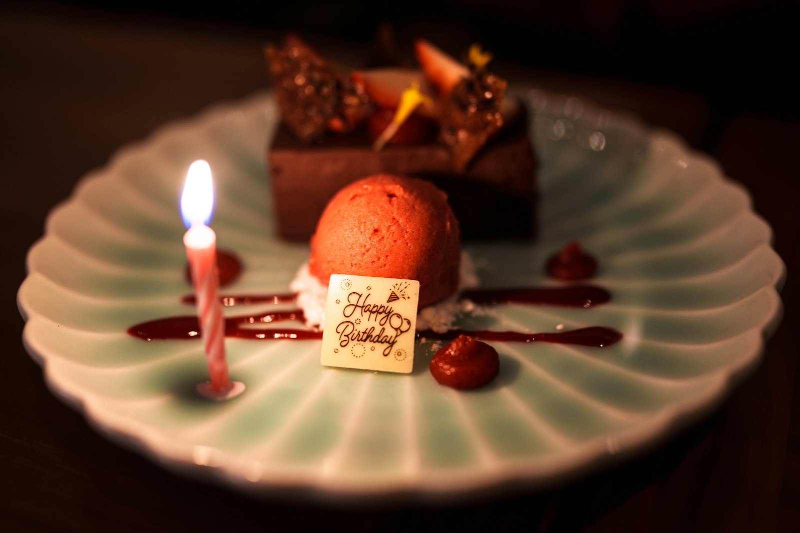 a white plate topped with a piece of cake and a candle